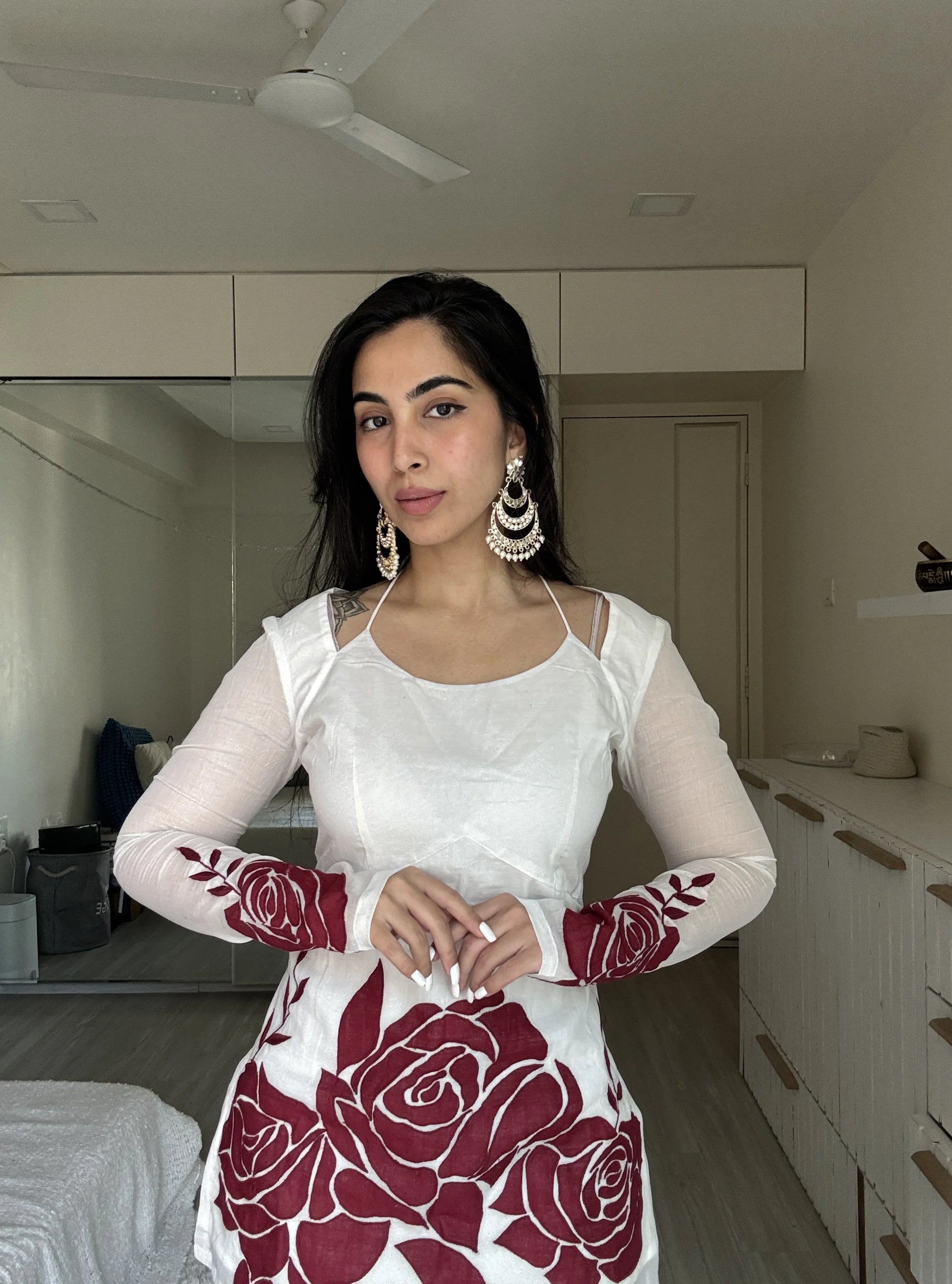 “Close‑up of red rose artwork on sleeves of Surbhi off‑white kurti”